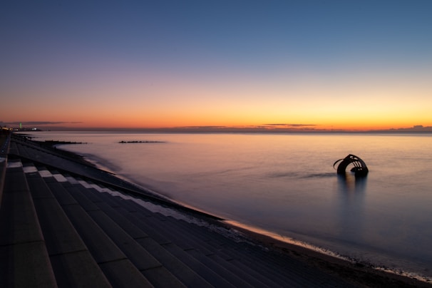 person walking on gray concrete pathway during sunset