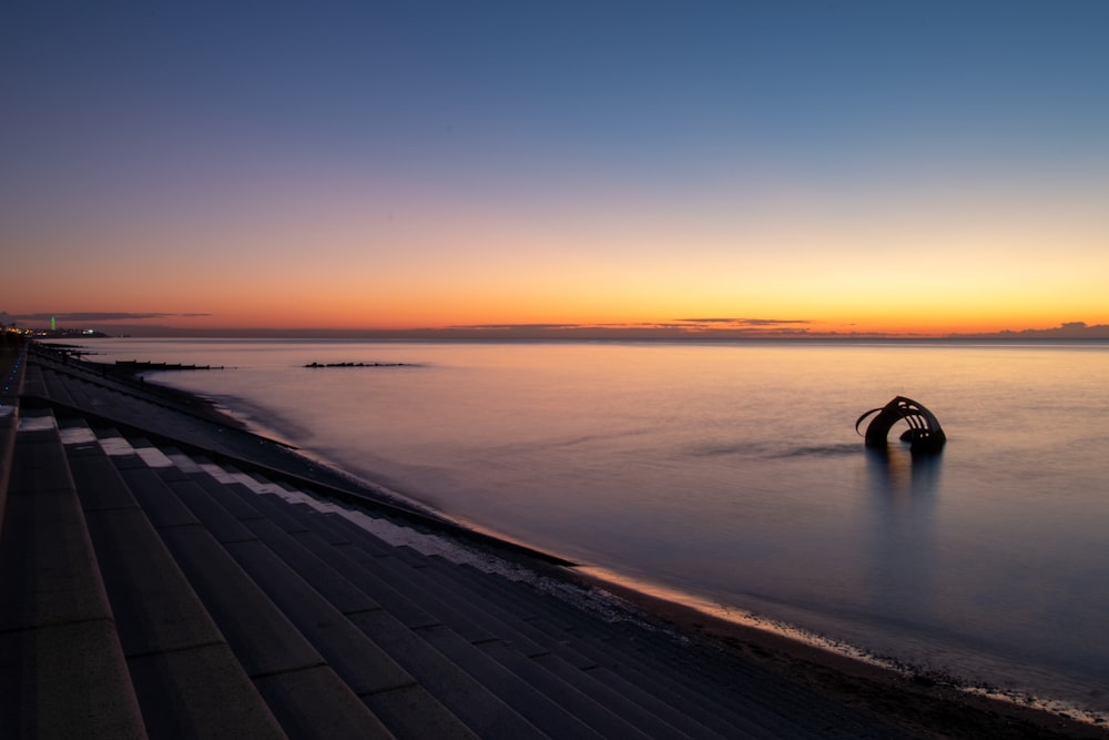 person walking on gray concrete pathway during sunset