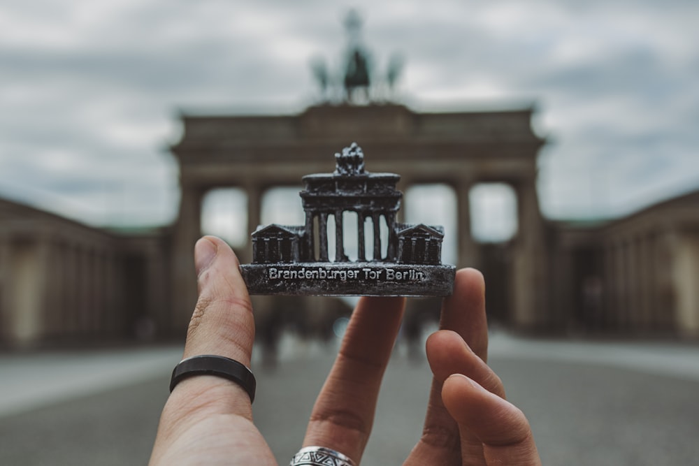 Persona sosteniendo un edificio en miniatura en blanco y negro