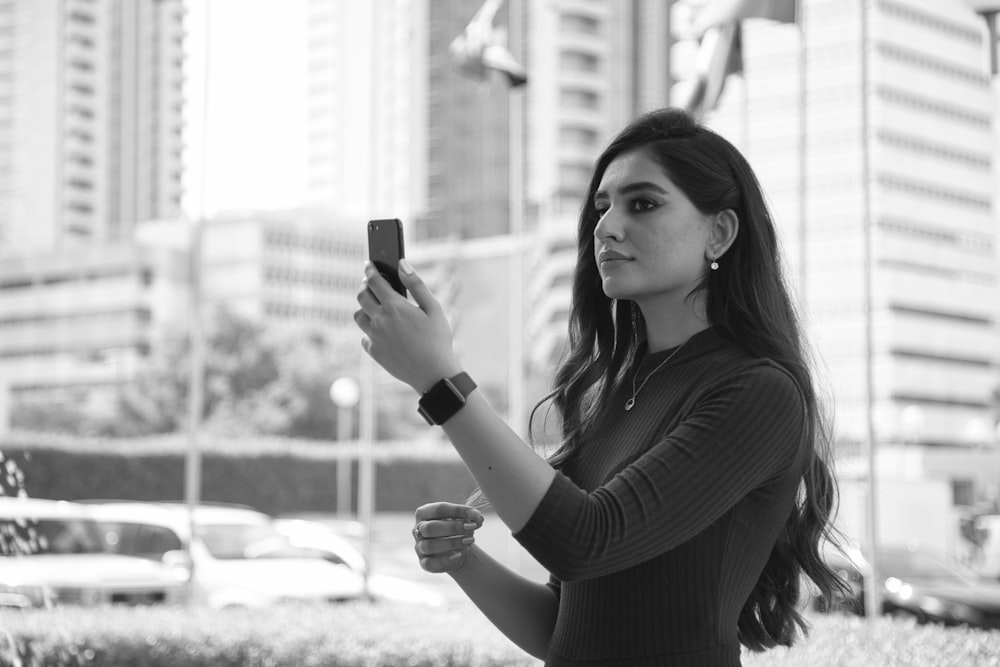 donna in camicia nera a maniche lunghe che tiene lo smartphone