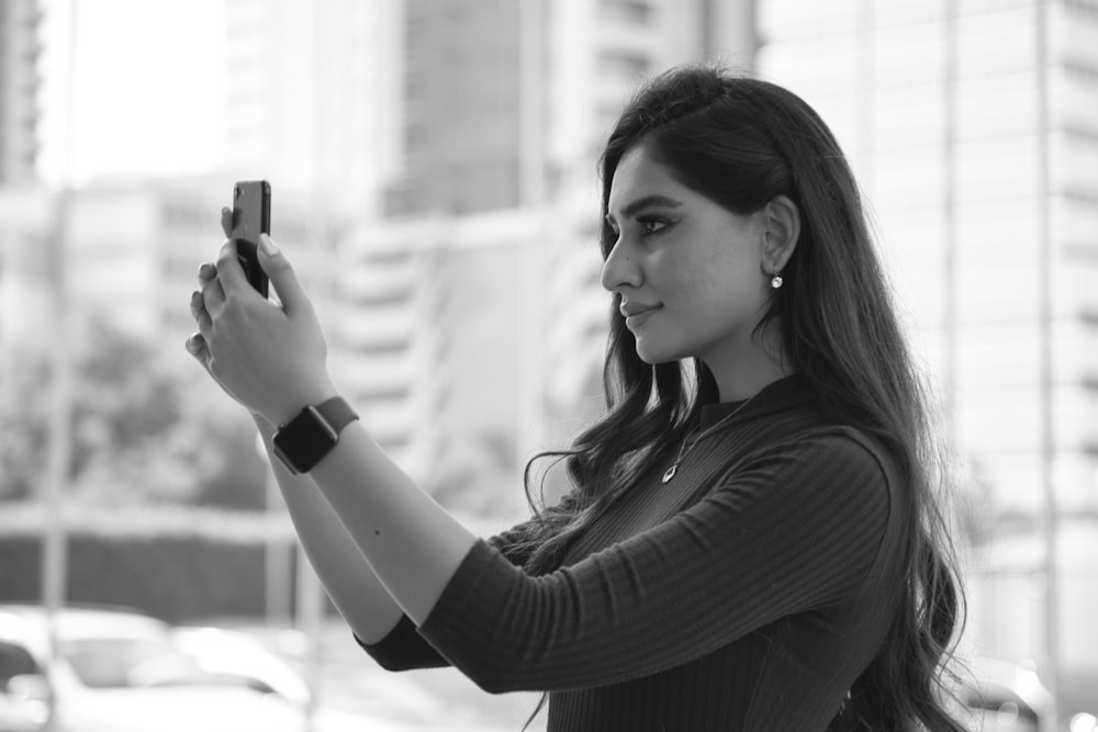 woman in black long sleeve shirt holding smartphone