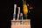 A neatly organized setup includes a blue-and-white toothbrush and an interdental brush in a holder. Beside them, a tube of toothpaste is placed, showcasing a modern and clean aesthetic. To the right, a small glass container holds vibrant yellow flowers and a single red rose, adding a touch of natural beauty.