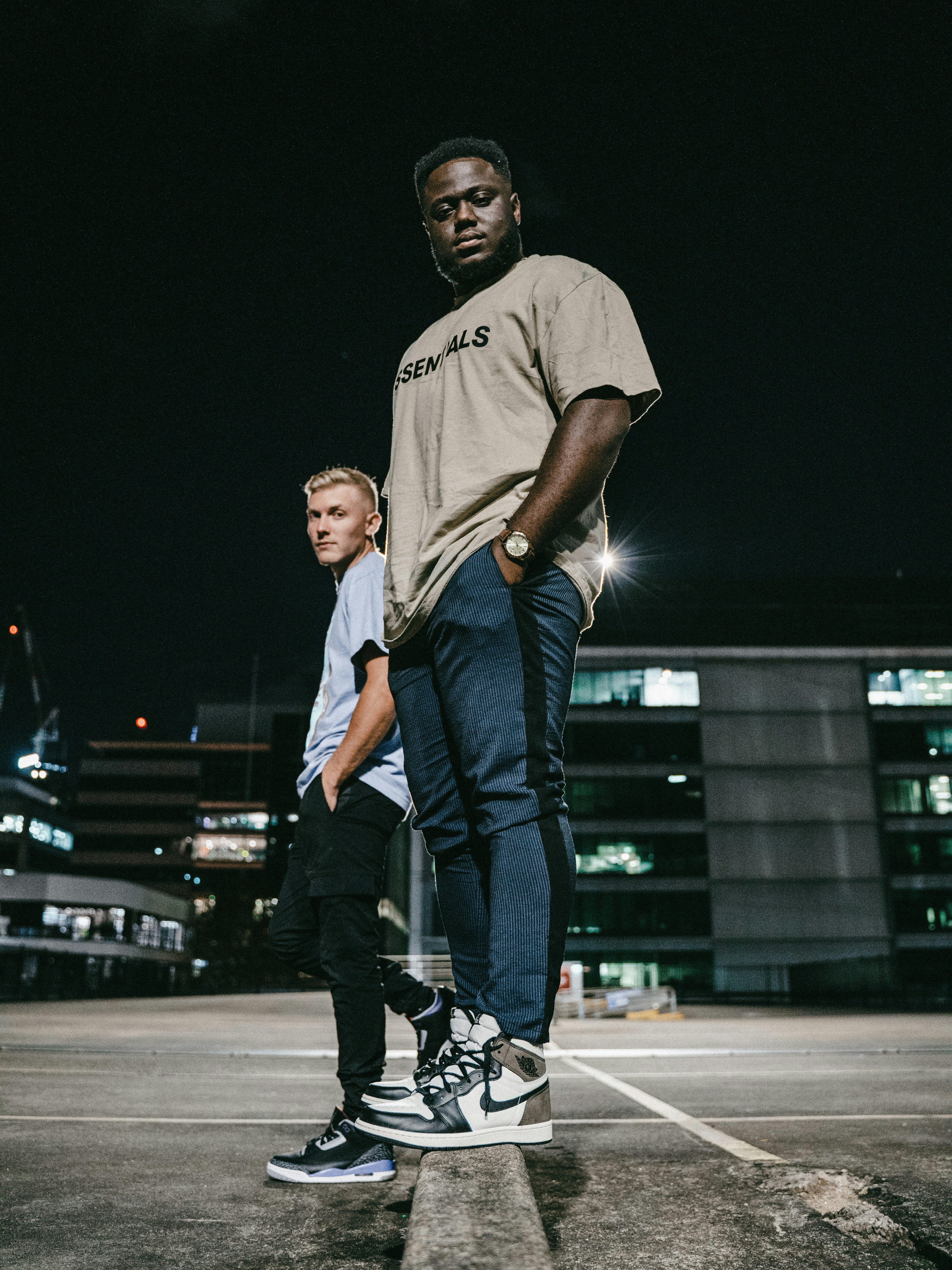 Homme en t-shirt à col rond gris et jean en denim bleu debout sur un sol en béton gris