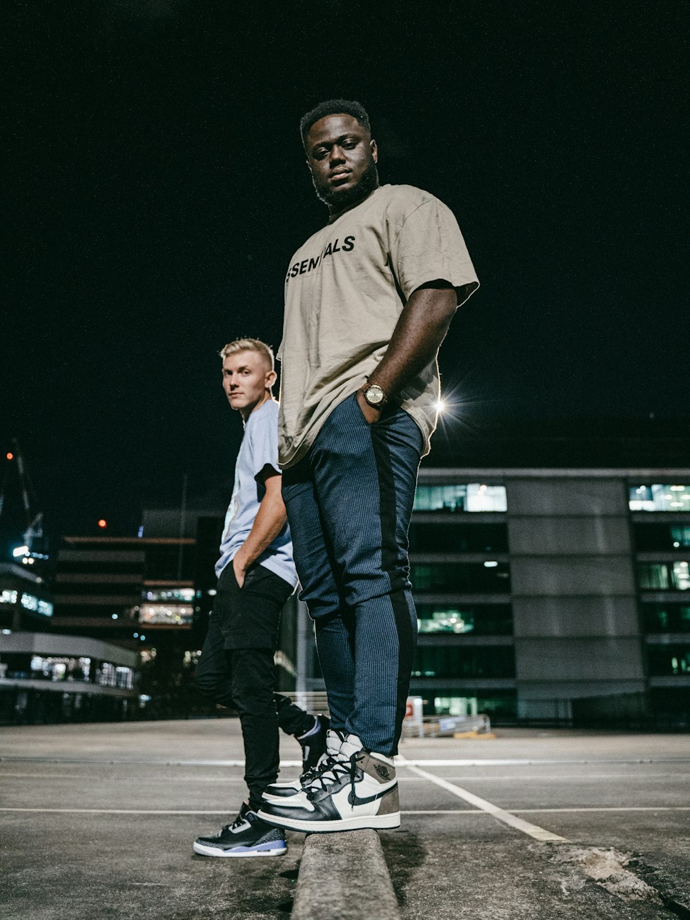 Mann in grauem Rundhals-T-Shirt und blauer Jeans auf grauem Betonboden