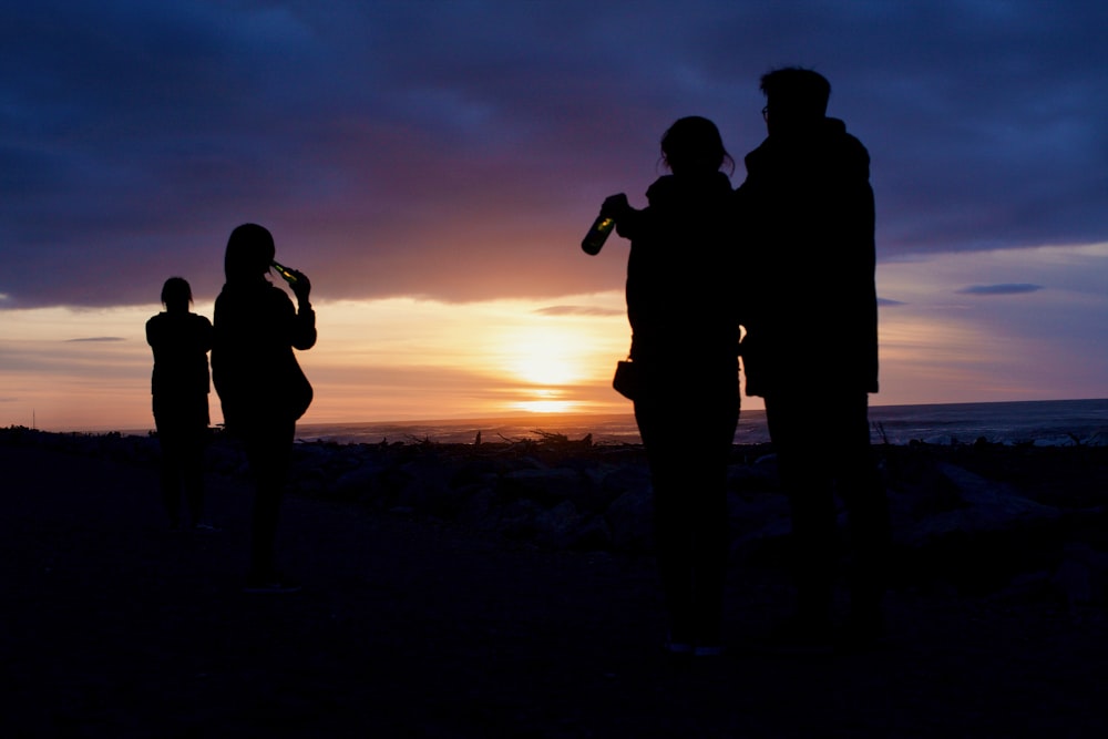 silhouette of 2 men standing on beach during sunset