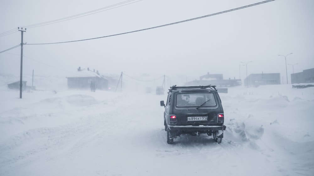 black suv on snow covered road during daytime