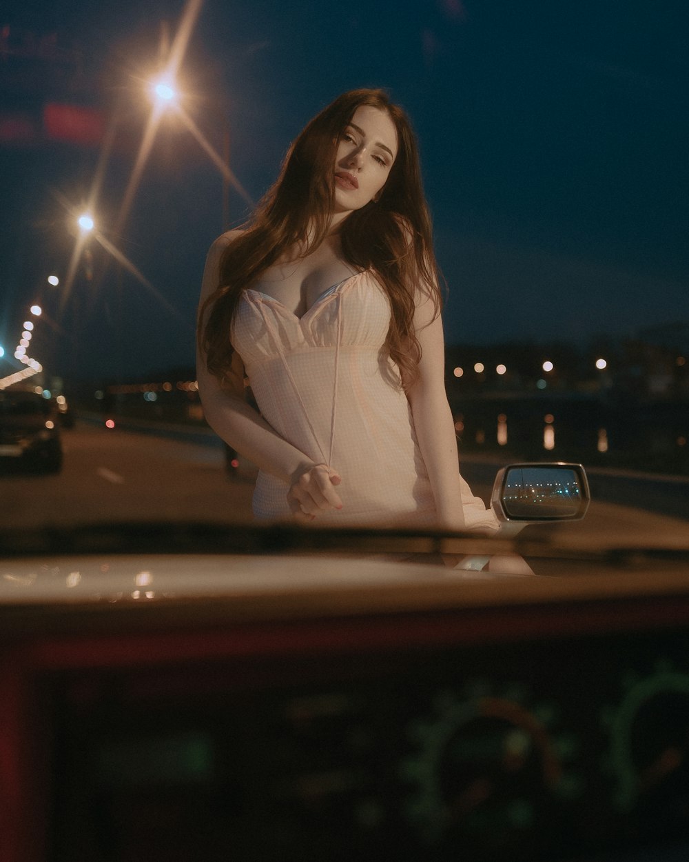 woman in white long sleeve shirt standing on road during night time