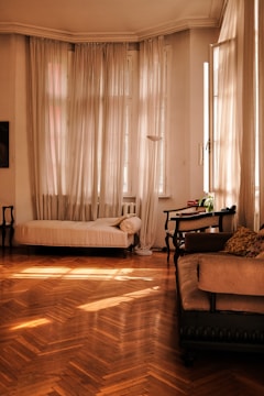 Living room with elegant window coverings and wooden flooring.