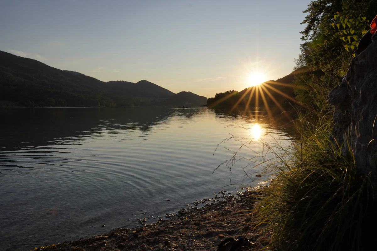 The sun setting over Fuschlsee, with wooded hills along the far shore