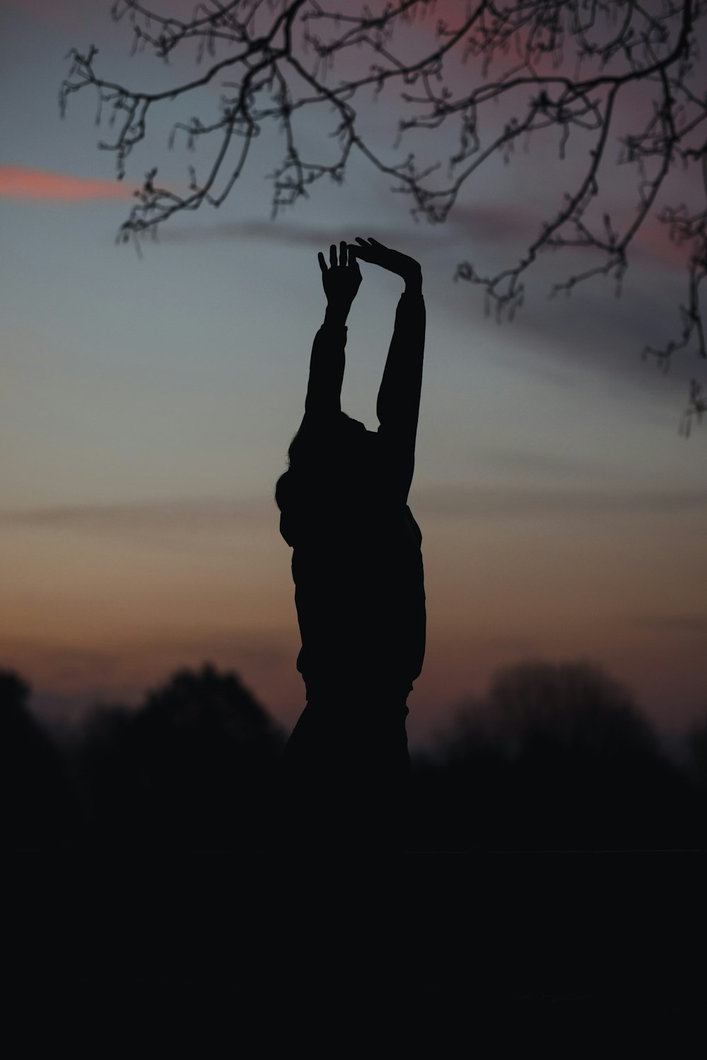 Silhouette eines Mannes, der während des Sonnenuntergangs die Hand hebt