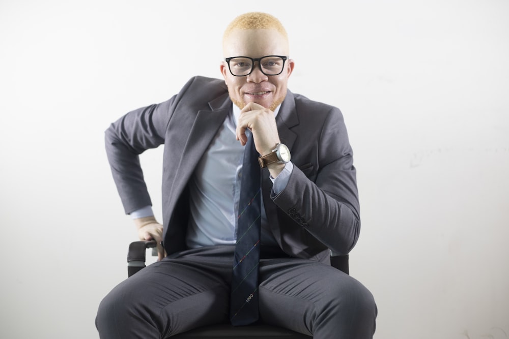 man in black suit jacket and black pants sitting on chair