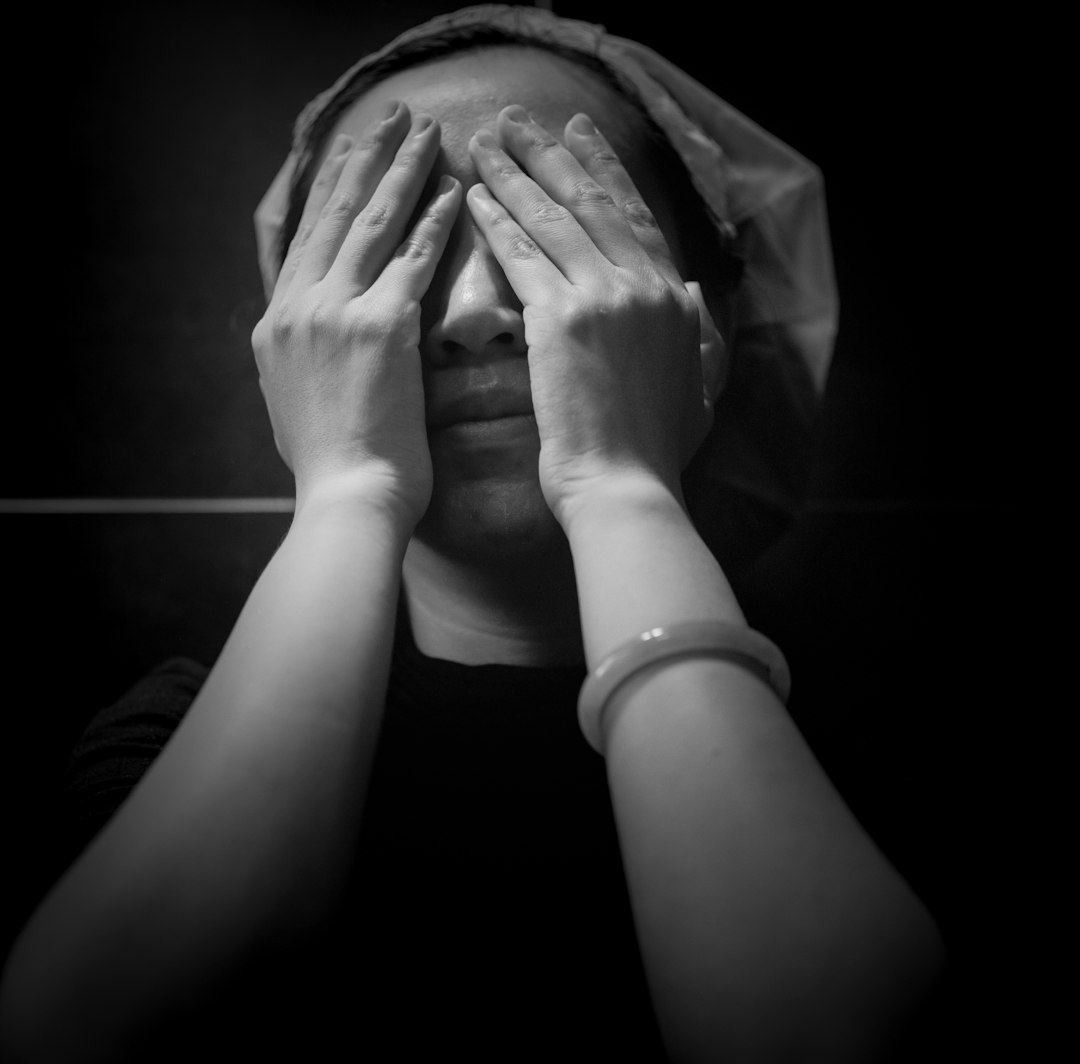 grayscale photo of person covering face with hands