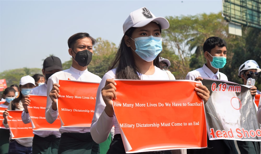 woman in white shirt holding red and white banner