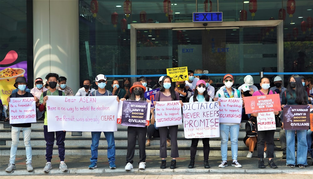 group of people holding white and red banner