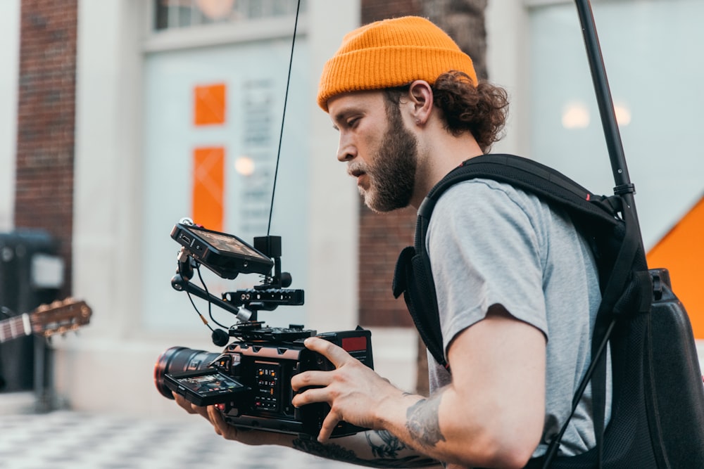 Mann im grauen Rundhals-T-Shirt mit schwarzer Videokamera