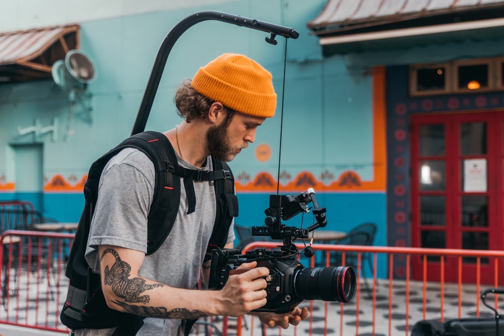 Mann in grauem Rundhals-T-Shirt mit schwarzer DSLR-Kamera