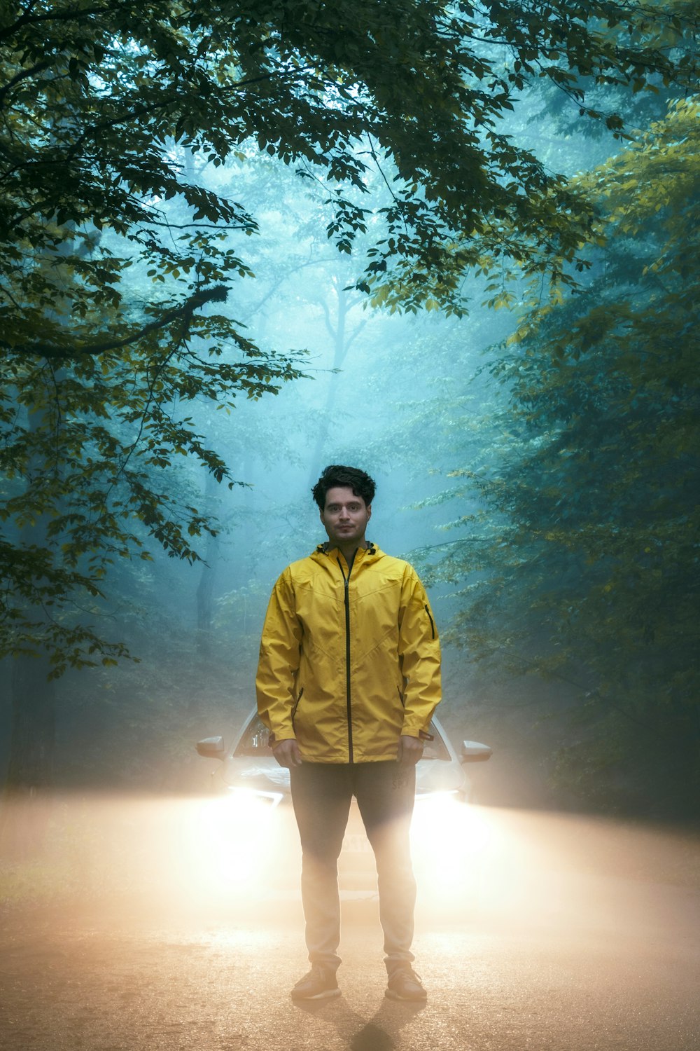 man in yellow jacket standing on forest during daytime