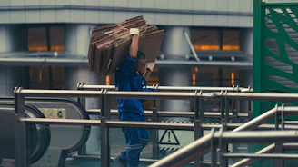 Delivery person carrying a large package up a staircase.