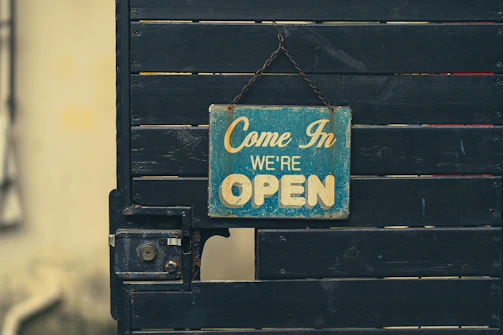 A bold, hand-painted banner hanging outside a local shop, inviting customers in.