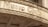 An old, weathered sign above an entrance labeled 'Music Club' is adorned with intricate floral carvings. The sign has a vintage appearance, with chipped and faded letters and a surface showing signs of aging.