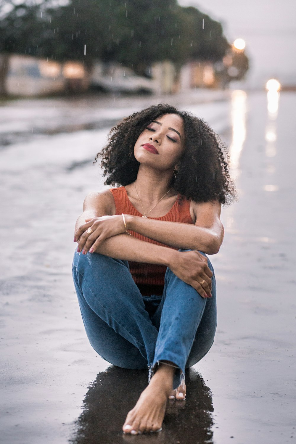 a woman sitting on the ground in the rain