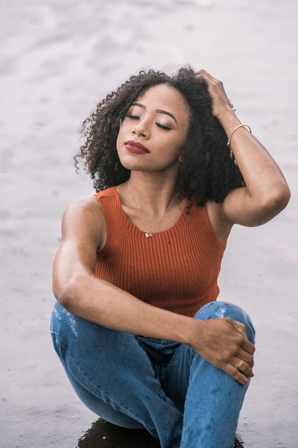 a woman sitting on the ground with her hands on her head