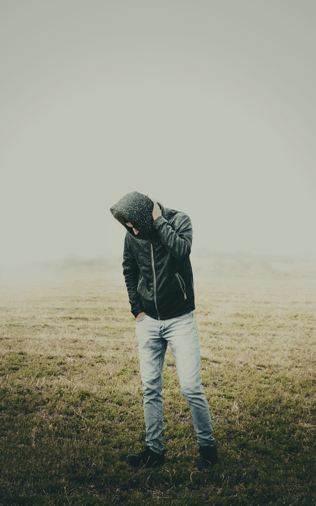 man in black jacket and white pants standing on green grass field during daytime