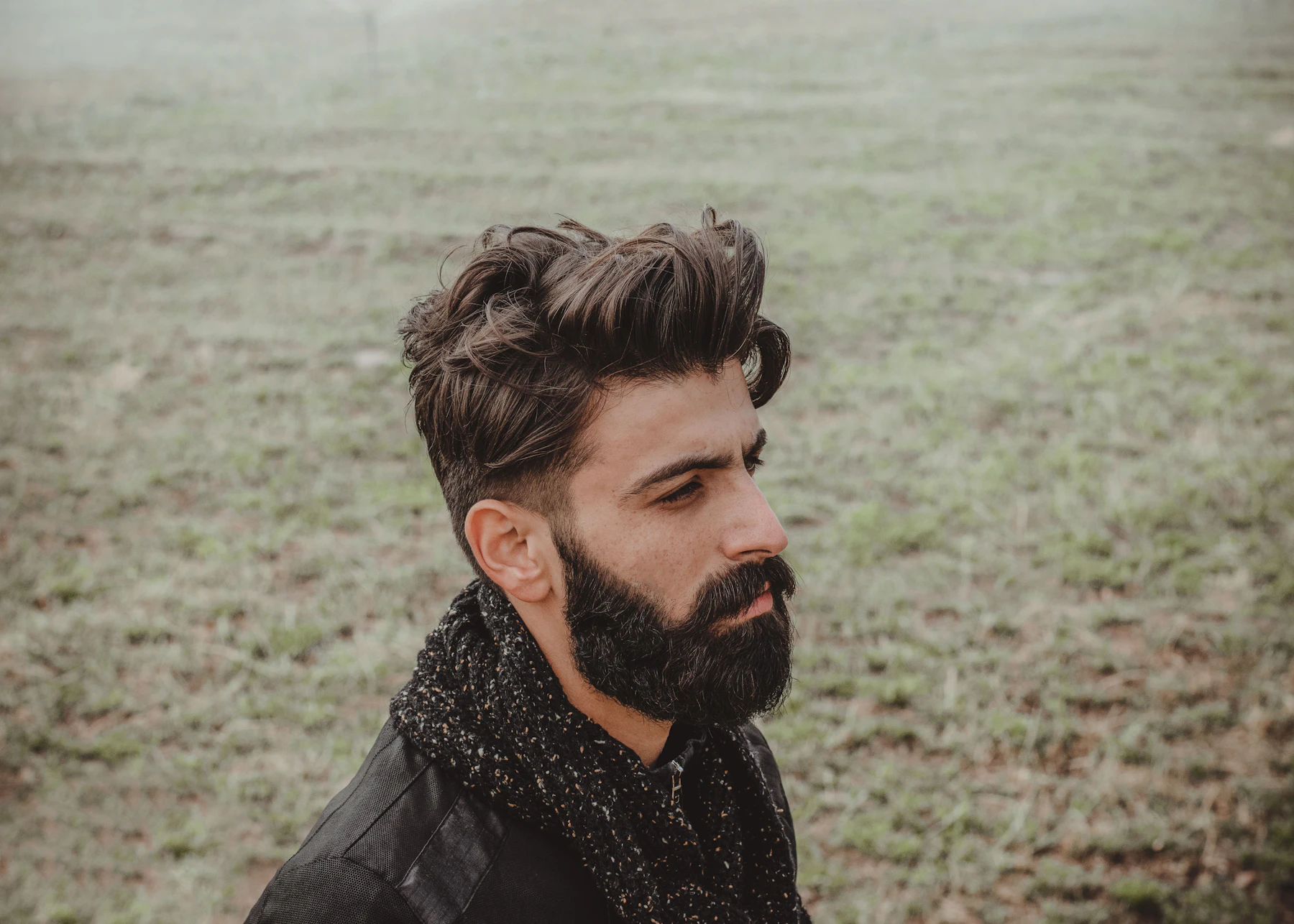 A man with full, dark hair and a beard outdoors