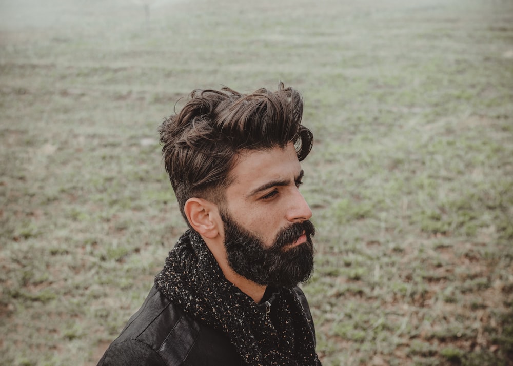 man in black leather jacket standing near body of water during daytime