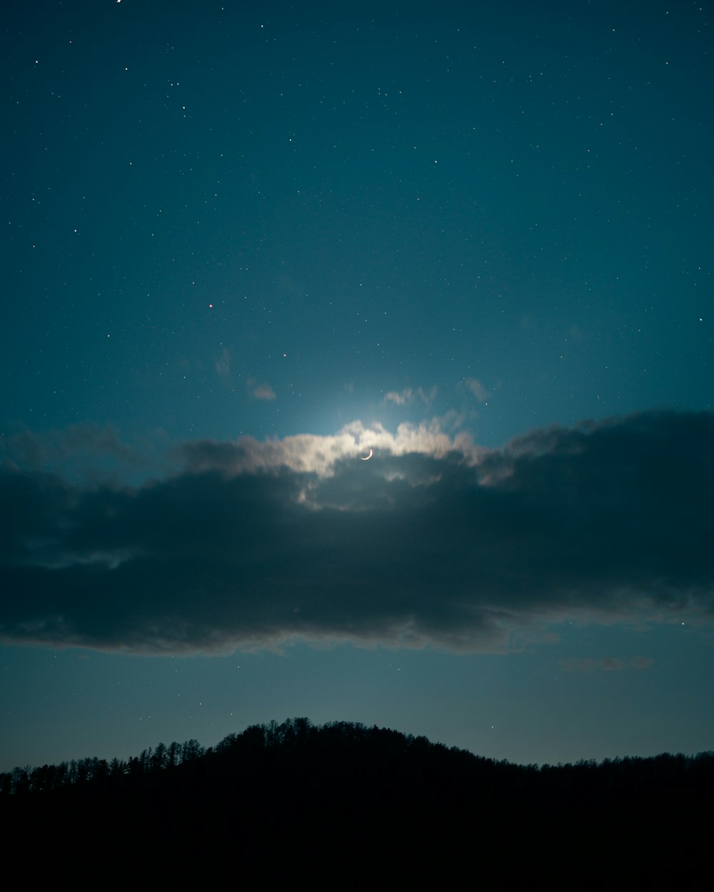 silhouette of trees under blue sky and white clouds during night time