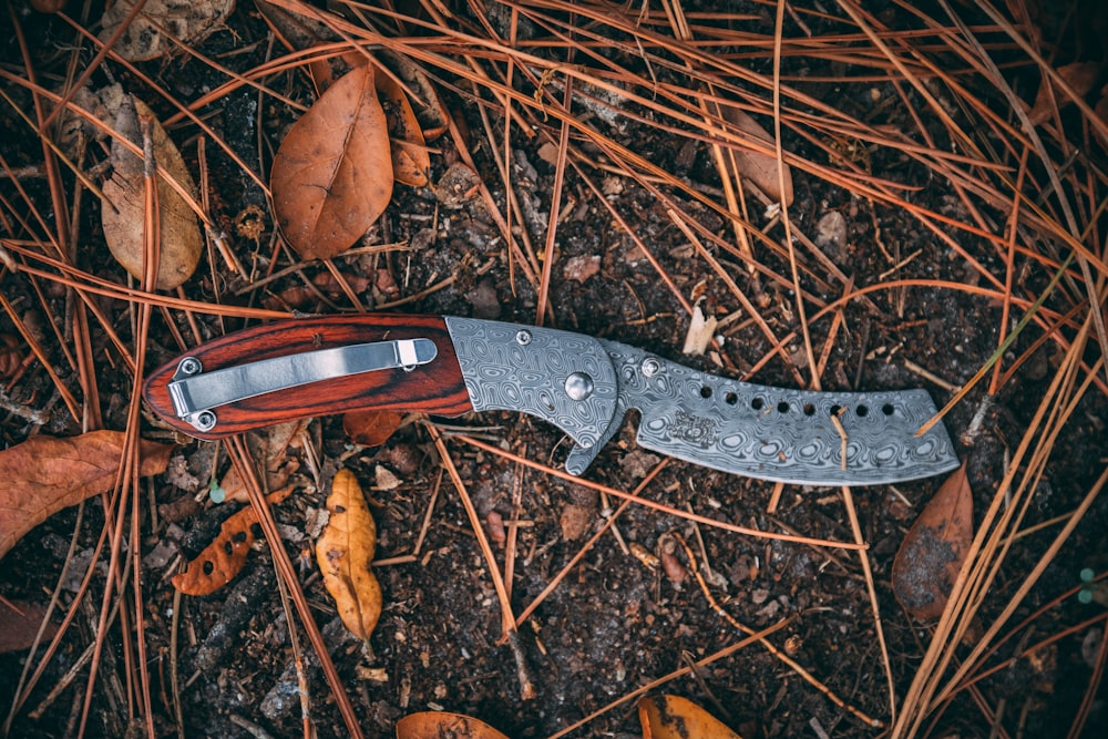 black and brown folding knife on brown dried leaves