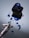 A fountain pen lies on a reflective surface next to an open ink bottle. Blue ink is splattered across the surface, creating a vibrant contrast against the smooth, mirrored background. The pen is elegantly designed, with a delicate floral pattern on its body.