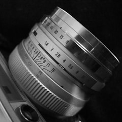 Close-up of a vintage camera lens with detailed focus and aperture markings, showcasing mechanical precision and craftsmanship in monochrome.