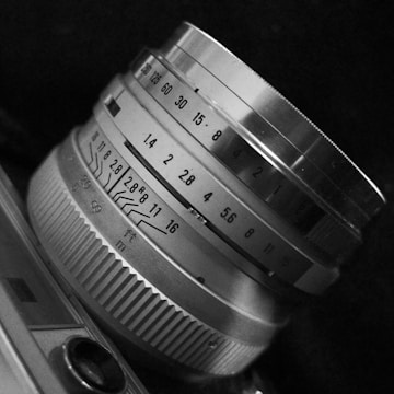 Close-up of a vintage camera lens with detailed focus and aperture markings, showcasing mechanical precision and craftsmanship in monochrome.
