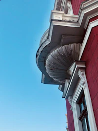 Close-up of a white EPS foam cornice with a smooth, durable red-coated surface installed on a modern building facade.