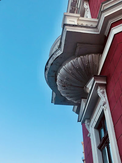 Close-up of a white EPS foam cornice with a smooth, durable red-coated surface installed on a modern building facade.