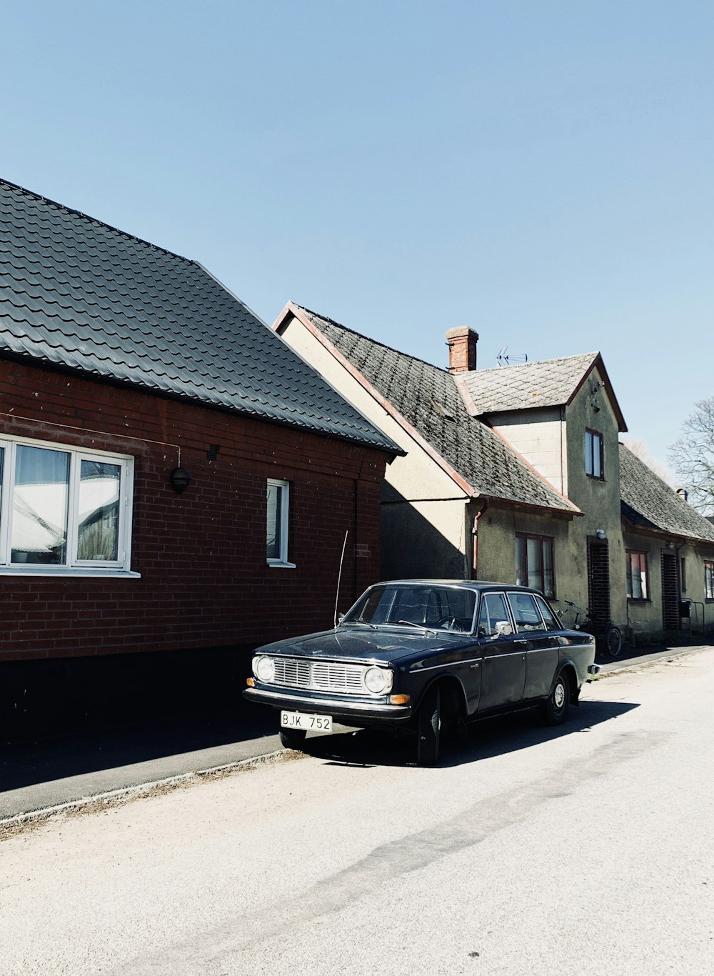 black car parked beside brown brick house