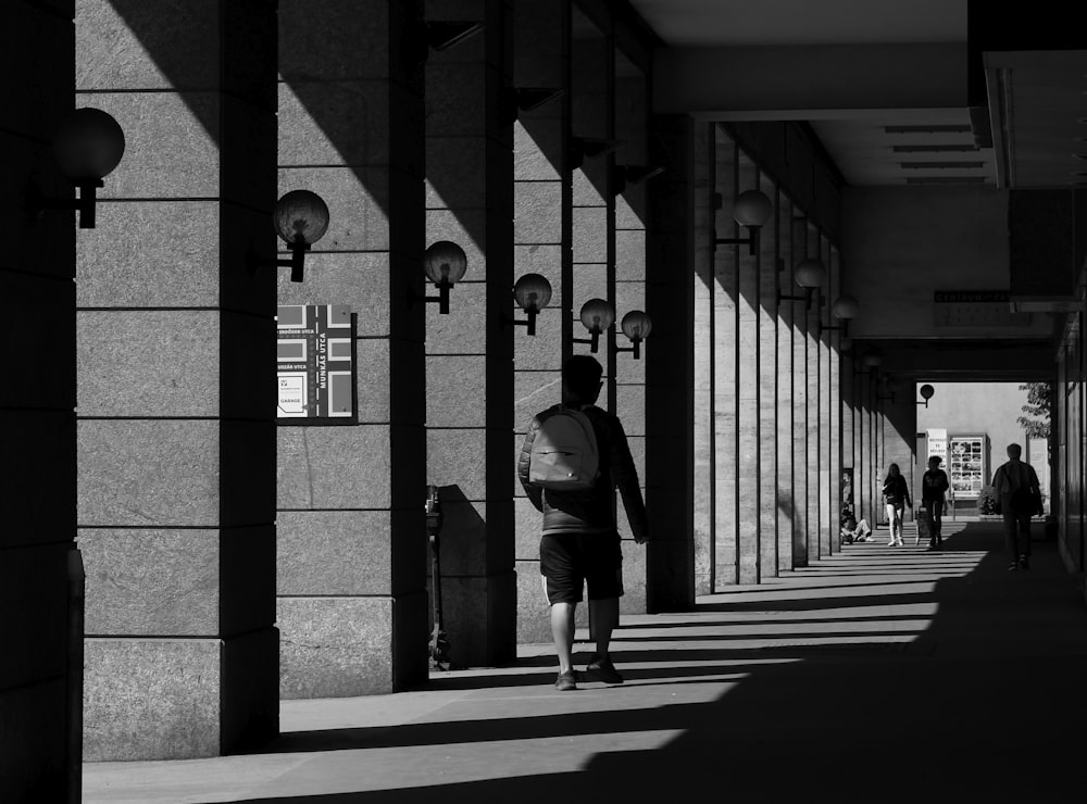 grayscale photo of man and woman walking on sidewalk