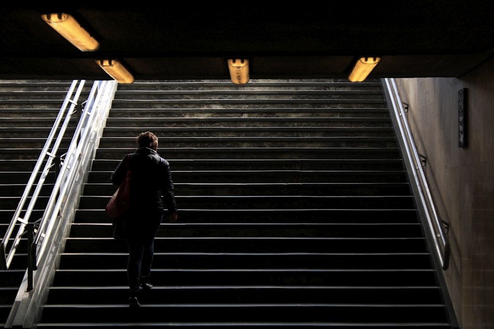 Hombre en chaqueta negra caminando por las escaleras