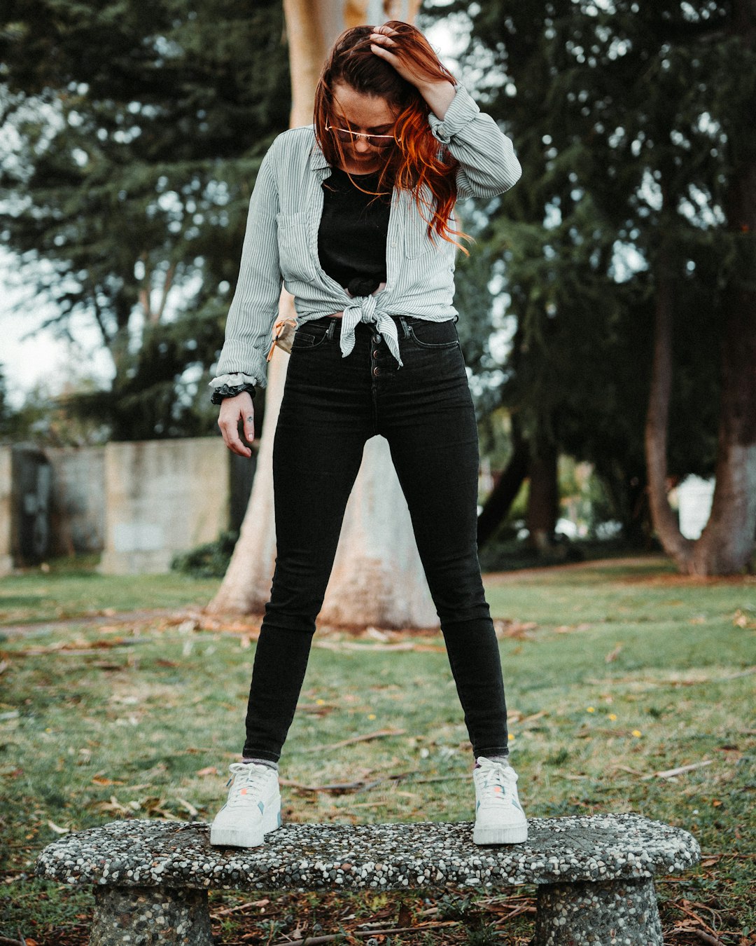 woman in gray long sleeve shirt and black pants standing on green grass field during daytime