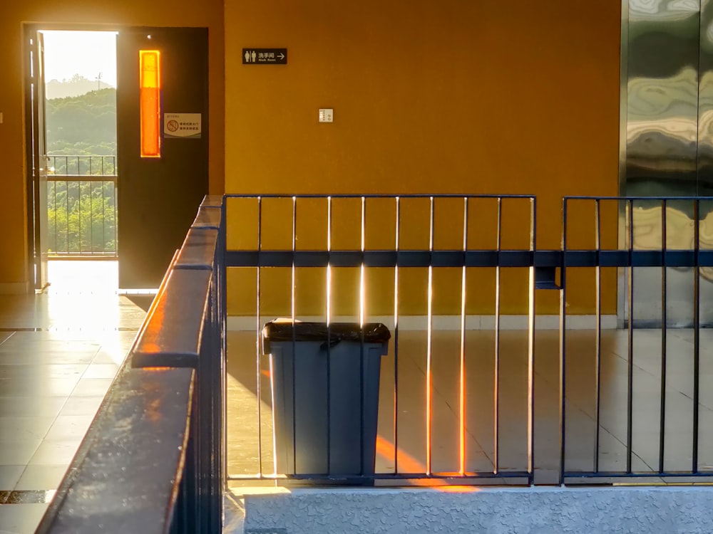 black trash bin beside brown concrete wall