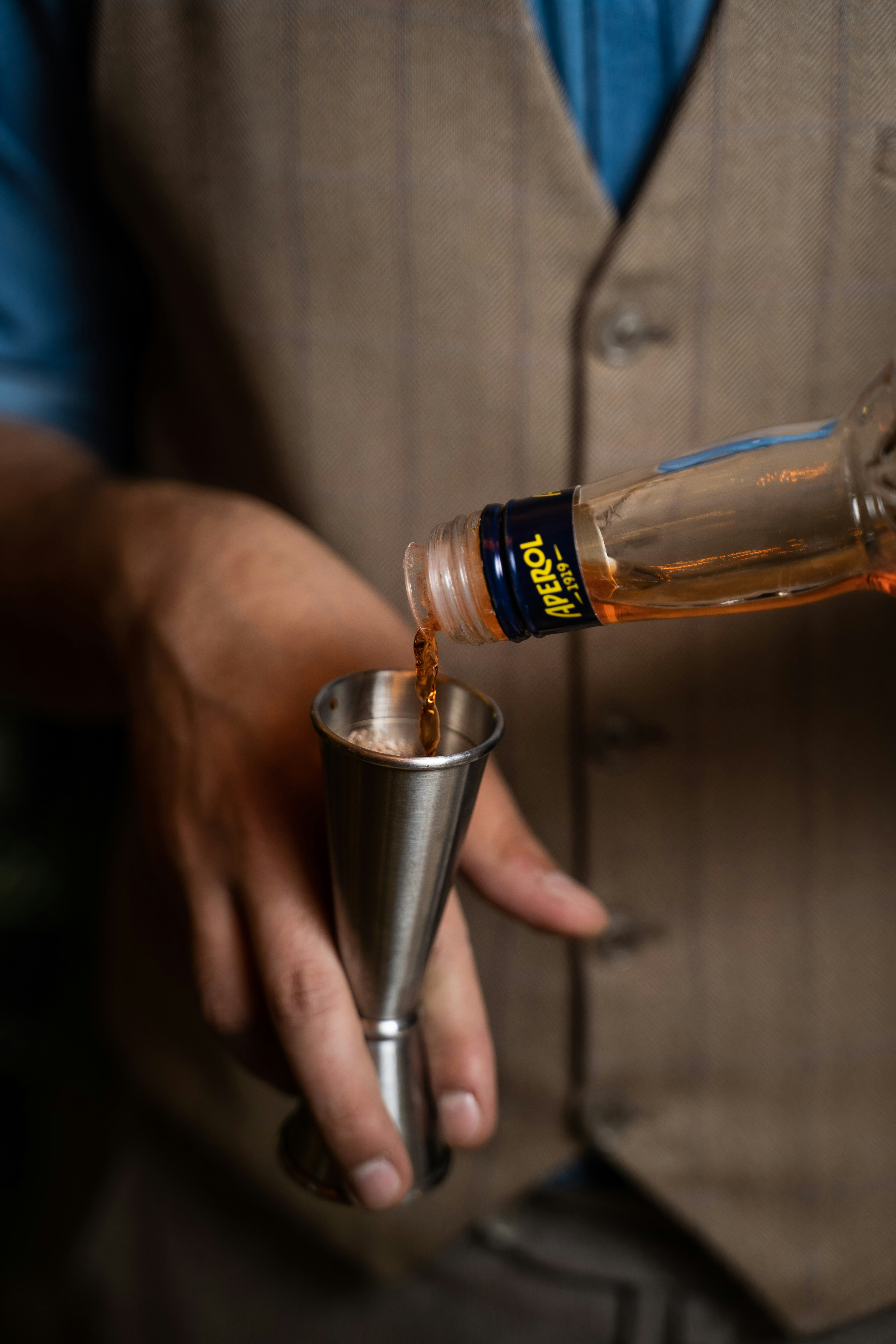 person pouring brown liquid on silver cup