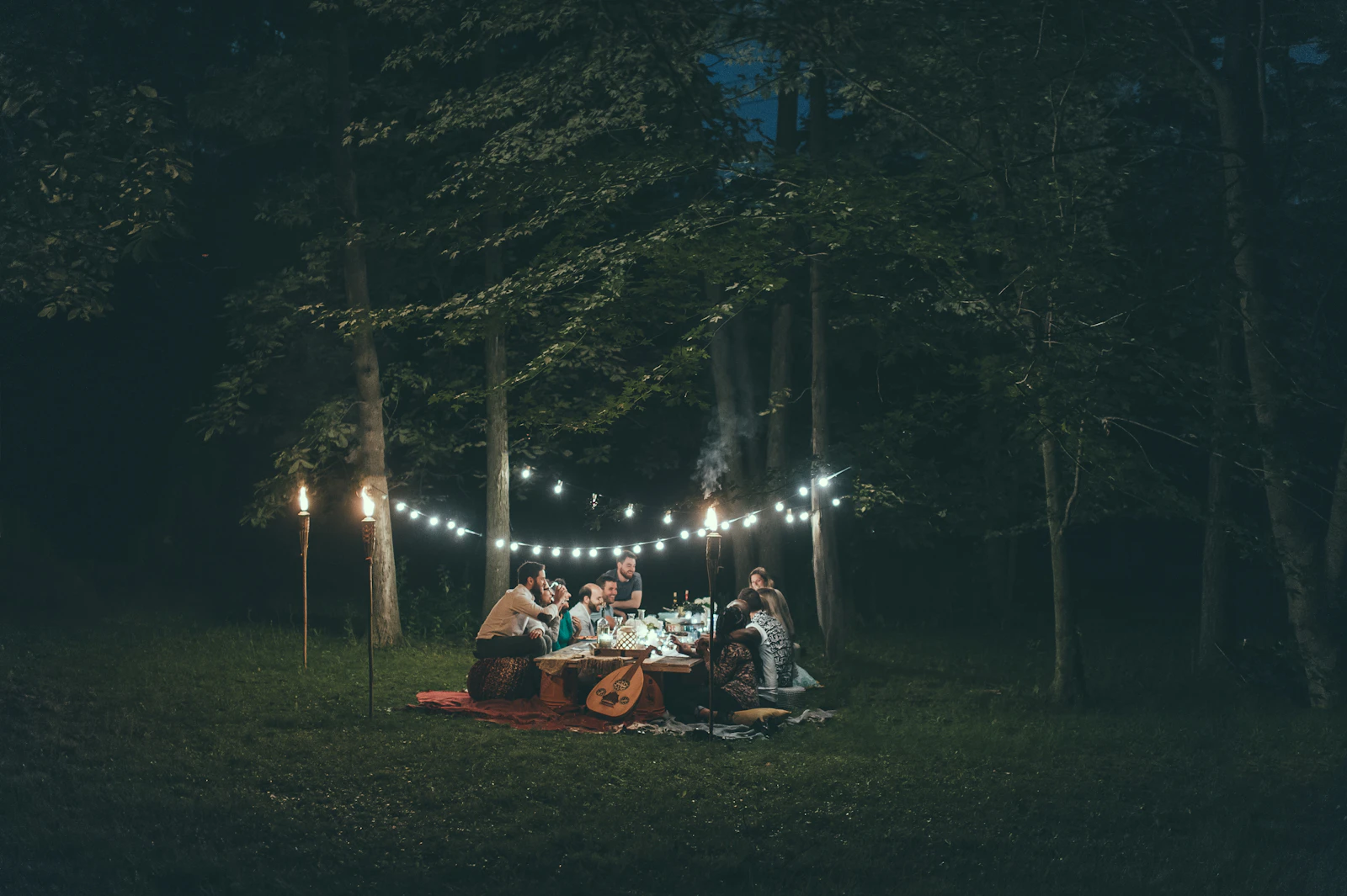 people gathered around a table under string lights at night