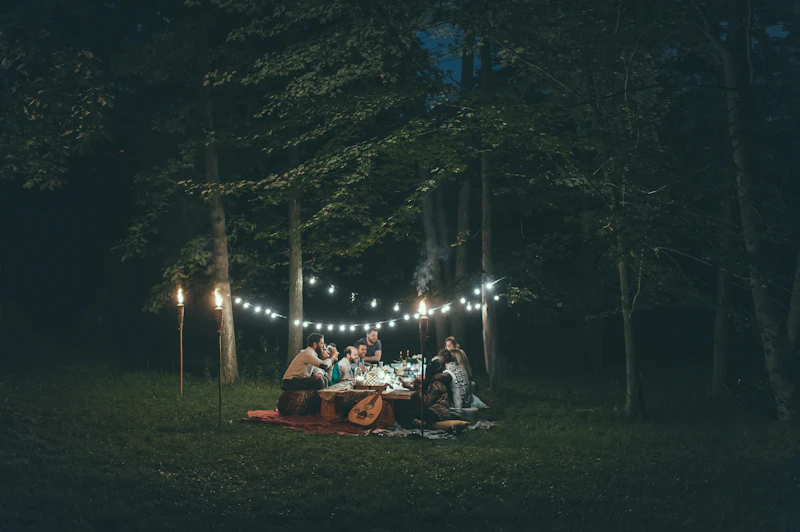 People gathered around a table under string lights at night