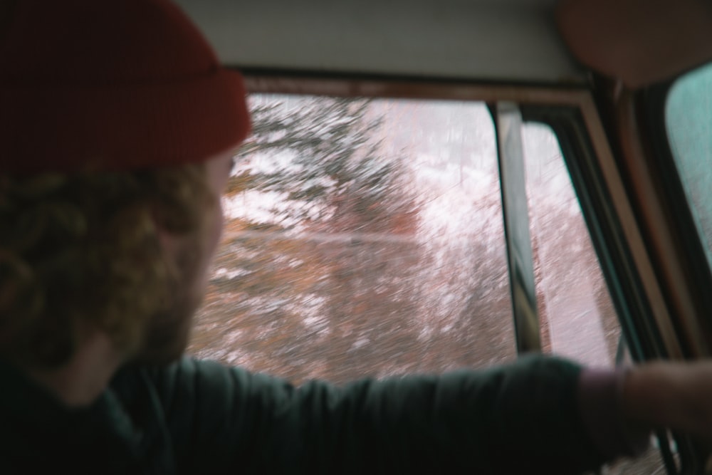 man in black jacket and red cap sitting inside car