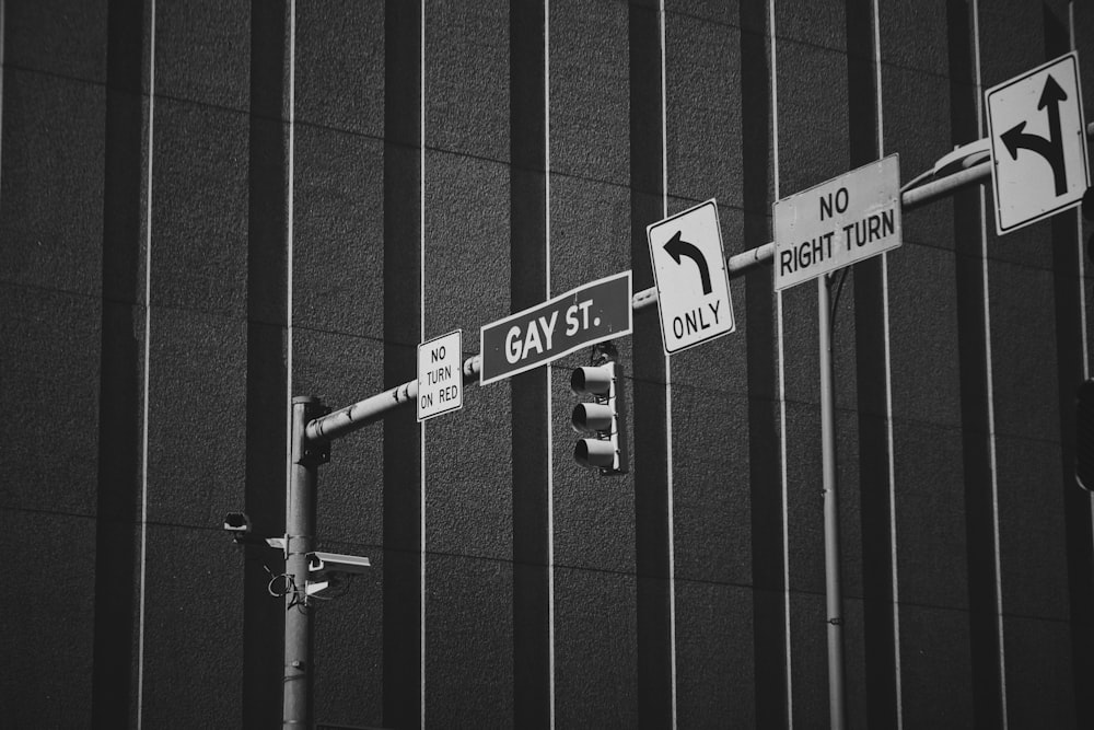 a black and white photo of street signs on a pole