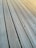 A close-up view of grooved wooden planks arranged parallel to each other. The surfaces have visible grains and knots, with metal screws securing them in place.