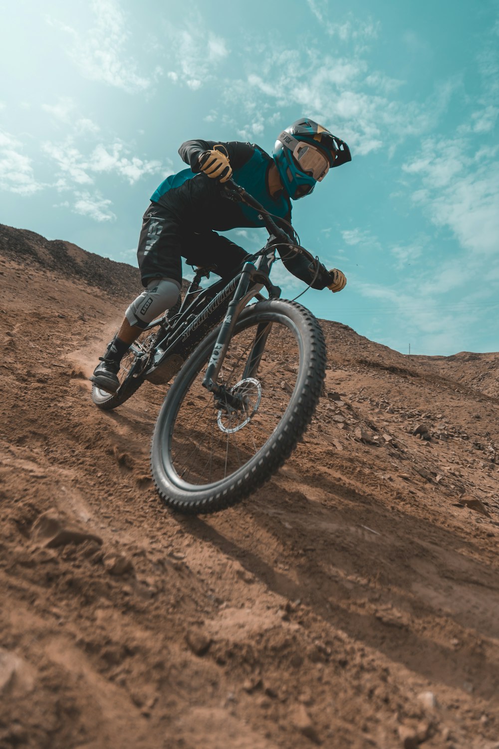 homme en veste noire sur un vélo de montagne noir sur un terrain brun pendant la journée