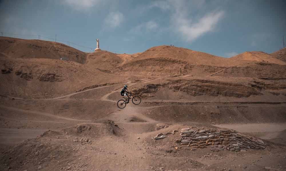 man in black jacket riding bicycle on brown sand during daytime