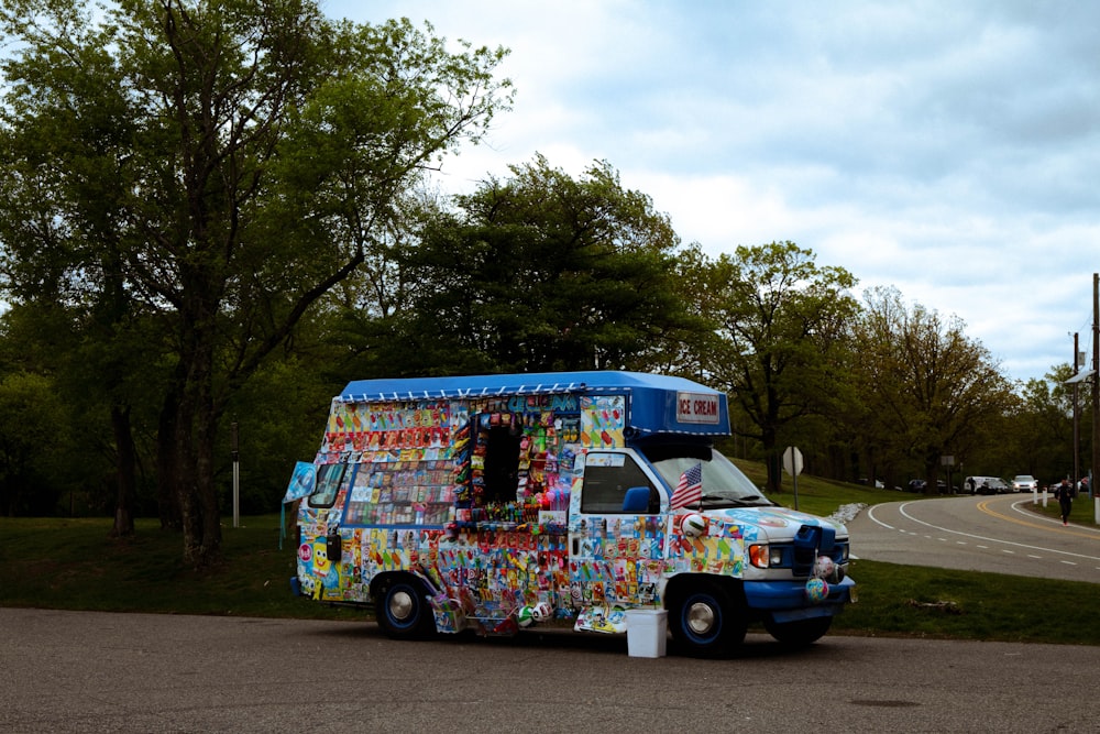 blue and white van parked beside green tree during daytime